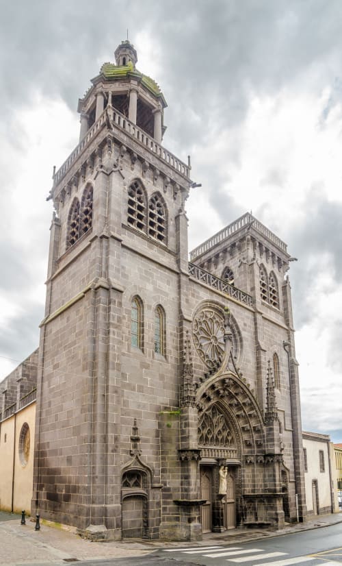 Gothic church facade in Riom, France with detailed stonework and ornate tower near La Caravelle hotel