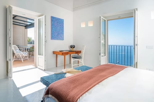 Camera luminosa a La Conciergerie Capri con vista mare, scrivania in legno e accesso a terrazza con vista sul Mediterraneo.
