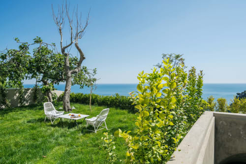 Giardino fronte mare con sedie e tavolo bianchi che si affacciano sul blu Mar Mediterraneo a La Conciergerie Capri