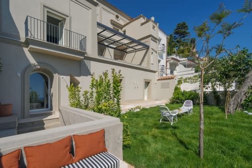 Esclusivo cortile di La Conciergerie Capri con sedute bianche, prato curato e architettura mediterranea