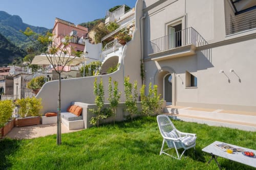 Terrazza giardino soleggiata a La Conciergerie Capri con lettino bianco, zona lounge e vista sulle montagne