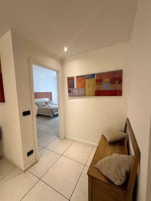 Moderno corridoio presso l'aparthotel Le Arche di Verona con sedie in legno e arte astratta colorata
