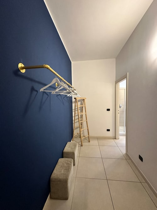 Ingresso moderno con parete in blu navy, appendiabiti in ottone, scala in legno e pavimento in piastrelle nell'appartamento Il Tenore B&B