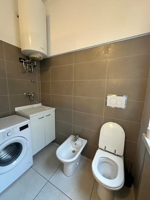 Bagno dell'appartamento Le Arche a Verona con toilette, bidet, lavatrice e scaldabagno