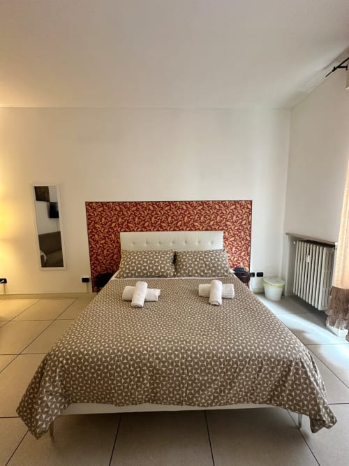Camera moderna dell'appartamento Le Arche a Verona con copriletto decorativo e testata rossa