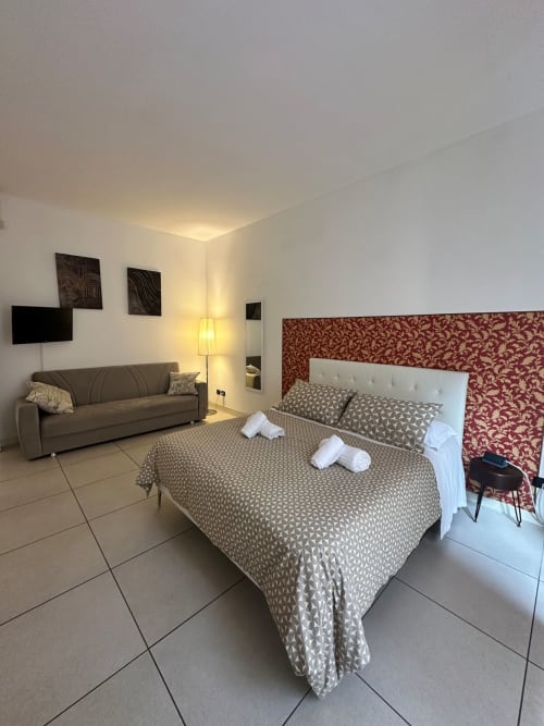 Moderna camera di studio presso l'hotel Le Arche a Verona con letto, divano, TV e illuminazione calda