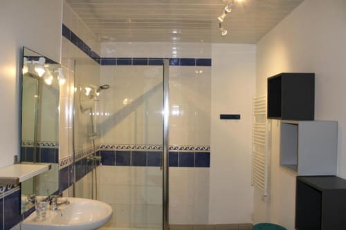 Modern bathroom with glass shower enclosure, dark tile accents, and vanity at Domaine des Piéris B&B