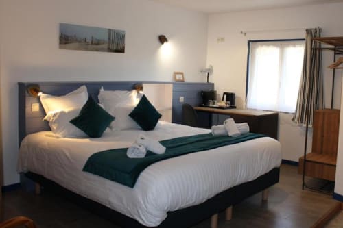 Comfortable double bedroom at Domaine des Piéris with white bedding, dark green accents, and garden view in Grandcamp-Maisy