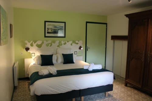 Comfortable double bedroom at Domaine des Piéris with lime green walls, dark wood furniture, garden view, and modern