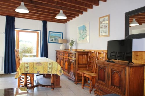 Spacious cottage dining and living area with wooden beams, TV, wooden furniture, and garden views at