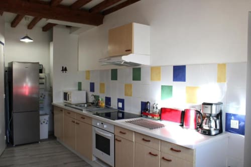 Modern kitchen in Domaine des Piéris cottage with colorful tile backsplash, wooden cabinets, stainless steel appliances and