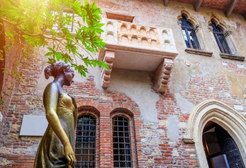 Statua dorata nel cortile dell'hotel Le Arche di Verona, circondata da affascinante architettura storica in mattoni e pietra