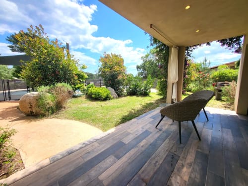 Villas Lantana Studio in Lecci mit Holzterrasse, Liegestuhl und gepflegtem Garten unter blauem Himmel
