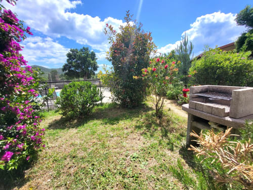 Vibrant garden patio at Villas Lantana in Lecci with magenta bougainvillea, flowering plants, and stone seating area