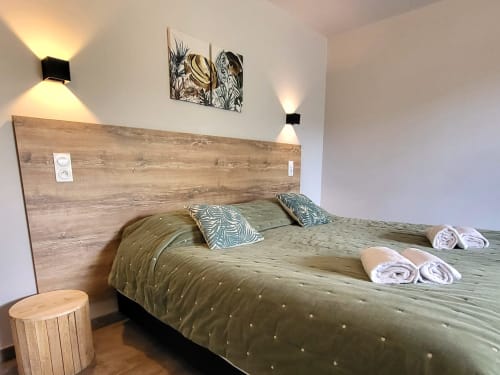 Modern bedroom at Villas Lantana in Lecci with wooden headboard, sage green bedding, and contemporary wall art