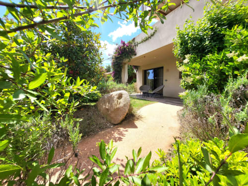 Lush garden pathway leading to Villas Lantana studio apartment in Lecci with terrace, vegetation, and stone accent