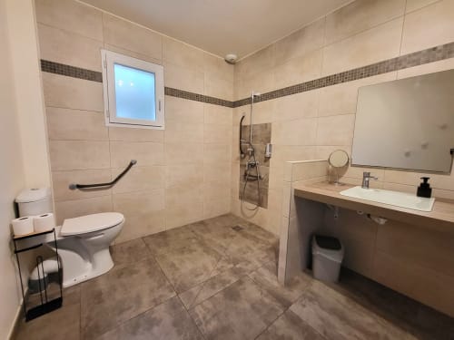 Modern wheelchair accessible bathroom with walk-in shower, toilet, and sink vanity at Villas Lantana villa in Lecci