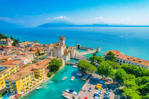 Castello medievale e città colorata su lago turchese con montagne, Verona Italia