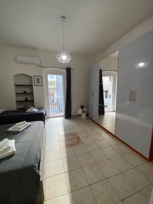 Camera da letto spaziosa a Newhouse Bari con letti gemelli, armadio con specchio, accesso al balcone e pavimentazione in piastrelle