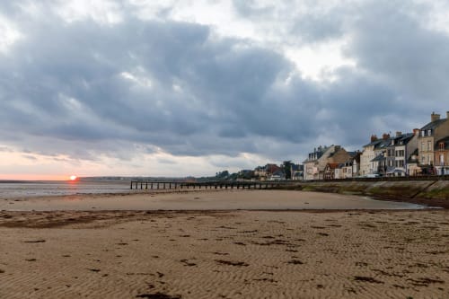 Coastal sunset view of Grandcamp-Maisy beach with traditional buildings and pier at Domaine des Piéris