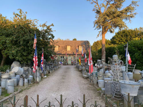 Domaine des Piéris B&B courtyard in Grandcamp-Maisy with stone pottery, flags, and brick building