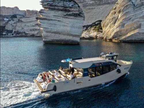Barca da pesca bianca ormeggiata vicino agli spettacolari scogliere calcaree bianche della Corsica, a Lecci presso Villas Lantana