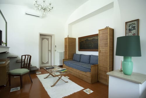 Elegante camera d'hotel a La Conciergerie Capri con mobili in rattan, letto daybed blu decorato, arredamento vintage e accenti verdi
