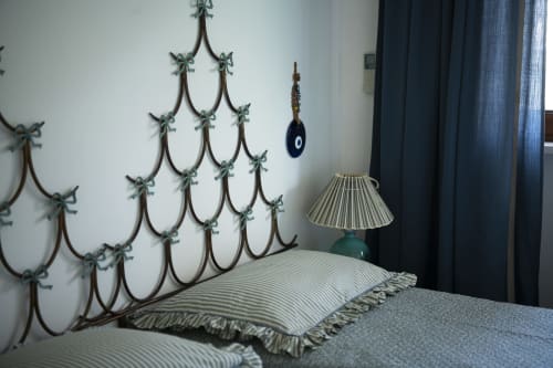 Camera da letto di La Conciergerie Capri con testiera in ferro battuto, cuscino rigato e lampada decorativa accanto a tende scure