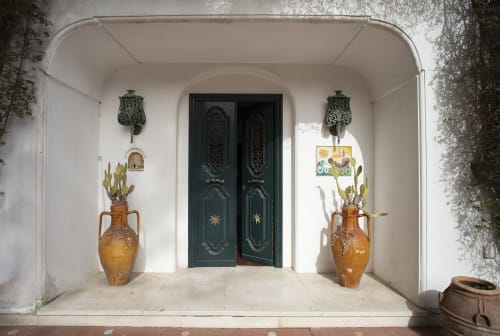 Elegante ingresso di La Conciergerie Capri con porte verde scuro, vasi in terracotta e applique decorative a Capri, Italia