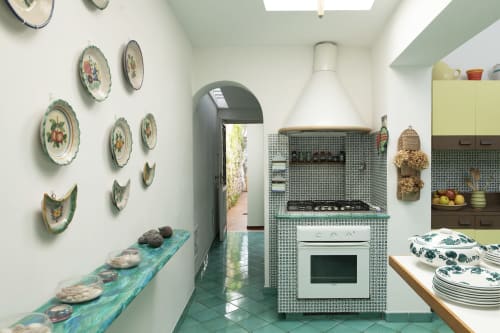 Affascinante cucina della Conciergerie Capri con piatti decorativi, bancone turchese e tradizionali piastrelle caprese