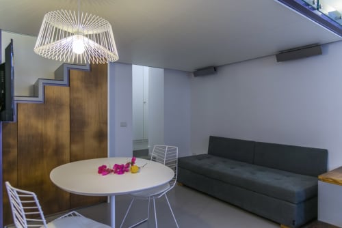 Suite moderna a La Conciergerie Capri con tavolo da pranzo, divano nero e illuminazione sospesa con vista su Capri.