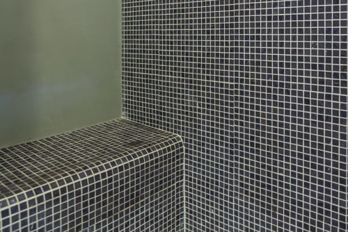 Angolo bagno con piccole piastrelle a mosaico all'Hotel La Conciergerie Capri, con panca curva e tonalità neutre