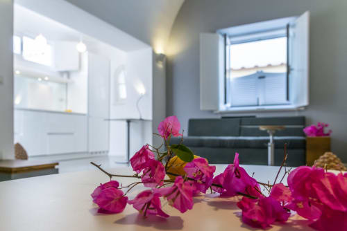 Camera luminosa del Capri Hotel con fiori di buganvillea magenta sul tavolo, vista sul mare dalla finestra e servizi moderni