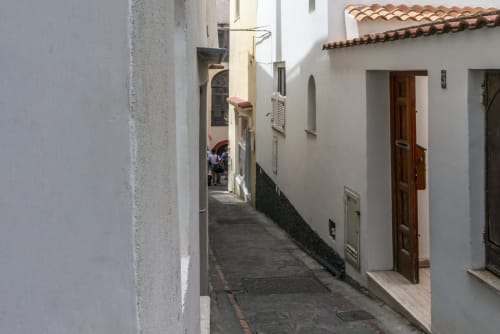 Stretto vicolo acciottolato dell'hotel La Conciergerie a Capri con edifici imbiancati e coppi in terracotta