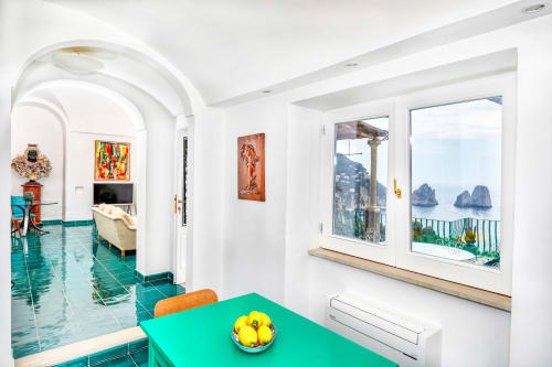 Cucina moderna e luminosa di La Conciergerie Capri con tavolo turchese e vista sul mare sui faraglioni