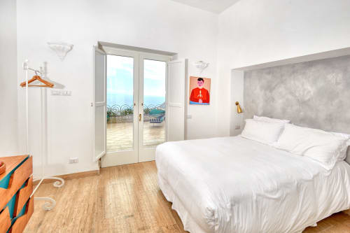 Camera luminosa a La Conciergerie Capri con biancheria bianca, balcone con vista mare, pavimenti in legno e arredamento costiero moderno
