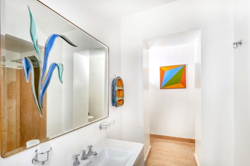 Bagno moderno dell'hotel La Conciergerie Capri con lavabo bianco, specchio, arte botanica blu e geometrie colorate alle pareti.