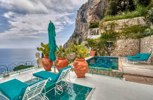 Terrazza lussuosa a Capri con lettini turchesi, ombrellone e vasi in terracotta con vista sul Mar Mediterraneo