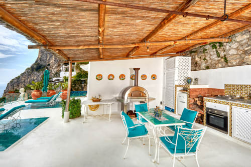 Terrazza esterna di La Conciergerie Capri con sedute turchesi, forno a legna e vista mare