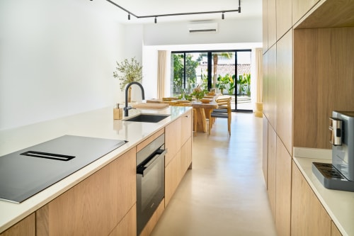 Cucina moderna di La Conciergerie Capri con mobili in legno chiaro, piani neri e vista sul giardino