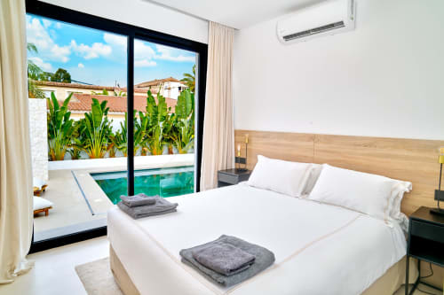 Camera da letto lussuosa a La Conciergerie Capri con vista sulla piscina, piante tropicali e servizi moderni