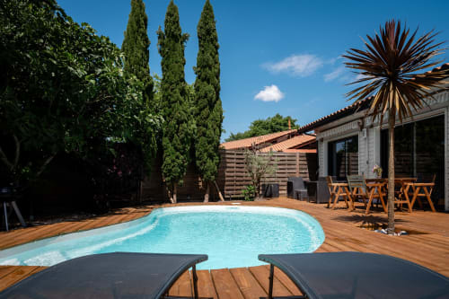 Villa Eden Bleu pool area in Biscarrosse with turquoise water, wooden deck, loungers, and palm trees