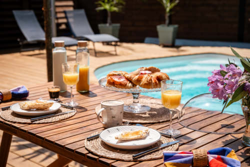 Luxury poolside breakfast at Villa Eden Bleu in Biscarrosse with croissants, fresh juice, and scenic garden views