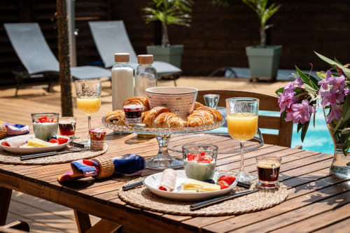 Breakfast spread at Villa Eden Bleu with croissants, fresh strawberries, orange juice, and poolside loungers in Biscarrosse.
