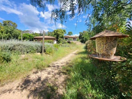Sentiero rustico in terra alle Villas Lantana a Lecci che conduce a cottages in pietra circondati da giardini rigogliosi e alberi