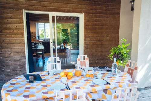 Aménagement de salle à manger en plein air à Villa Le Maquis Plage avec nappe à motifs, couverts, oranges fraiches et bois moderne