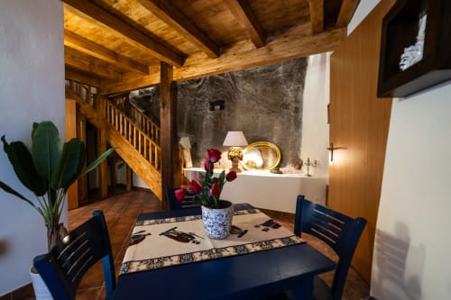 Sala da pranzo rustica con travi in legno a Casa Fiore del Borgo, Castiglione di Sicilia, con sedie blu e fiori rossi