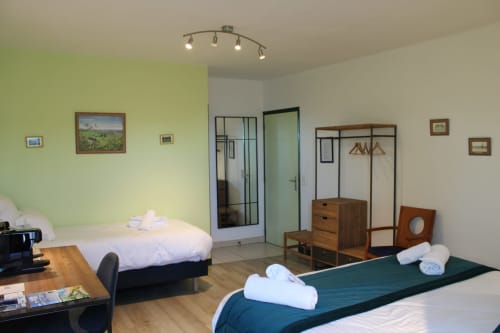 Triple bedroom at Domaine des Piéris B&B in Grandcamp-Maisy with two beds, wooden furniture, and garden view