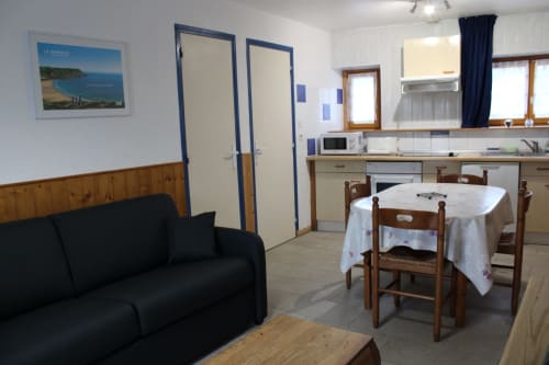 Spacious gîte interior at Domaine des Piéris with black sofa, dining table, equipped kitchen, and garden view