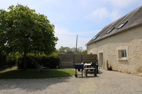 Stone cottage garden at Domaine des Piéris with BBQ, patio furniture, and manicured lawn in Grandcamp-Maisy